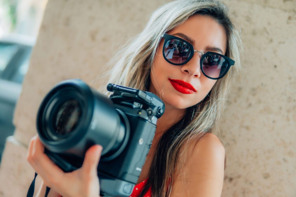 Video portrait, a girl holding professional photography camera in palm beach